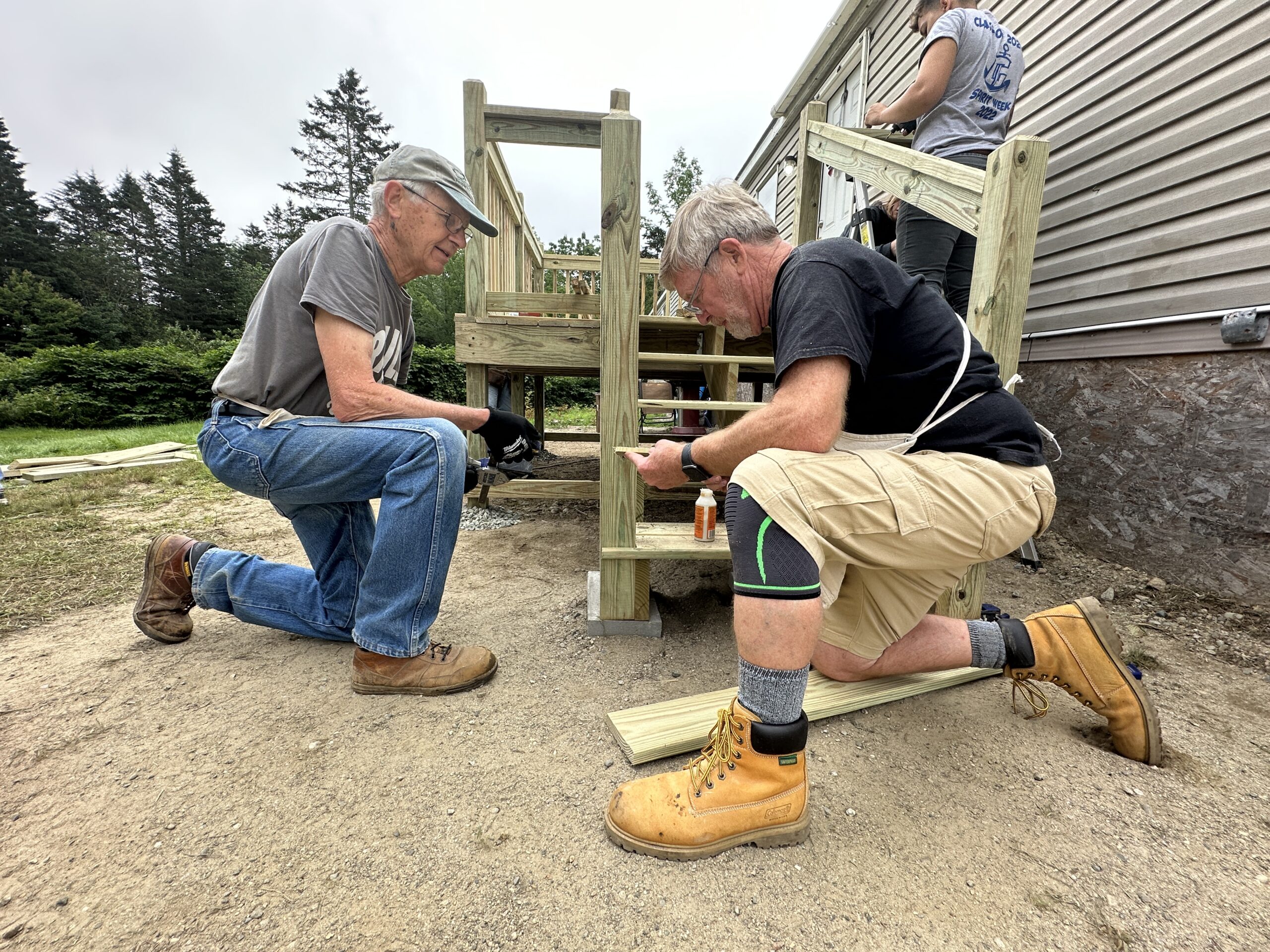 Two older white men work on a set of stairs