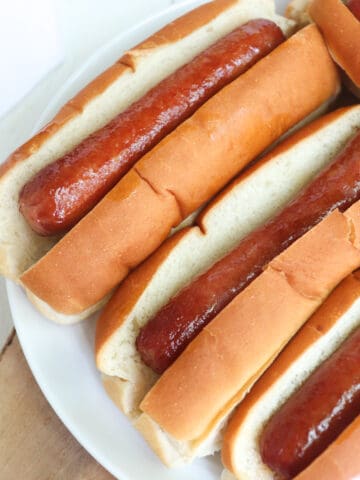 four air fried hot dogs on a white plate.