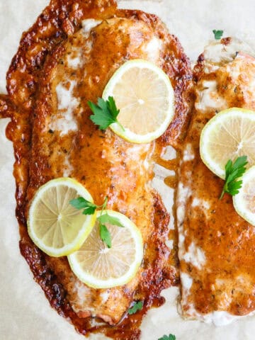 finished baked salmon with mayonnaise with lemons and herbs on top.