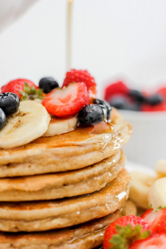 Gluten Free Banana Oat Protein Pancakes stack of 4 with fruit and syrup on top