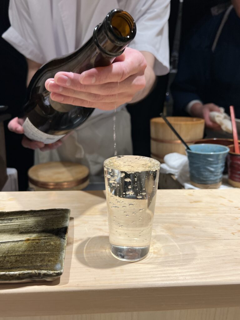 銀座鮨処まぐろ相馬水産で日本酒を注がれるシーン