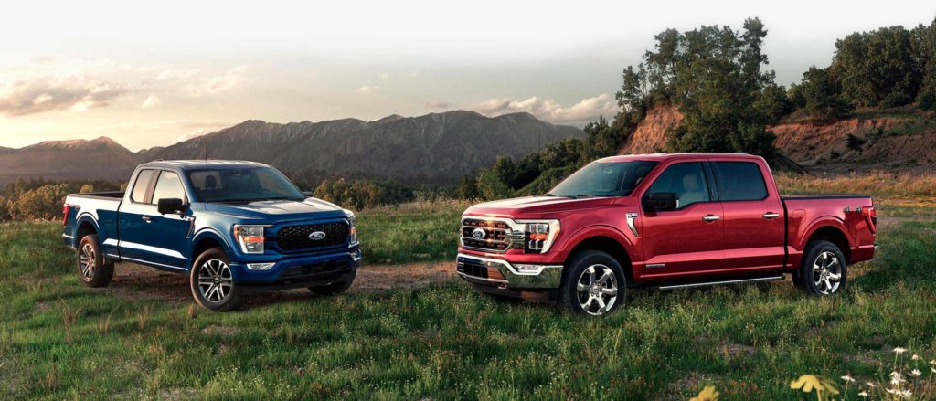 red and blue trucks on a grassy trail