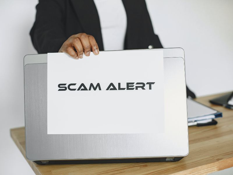 a person holding a scam alert sign