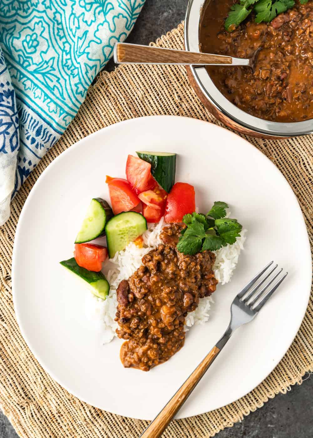 black dal makhani served over rice with vegetables on white plate