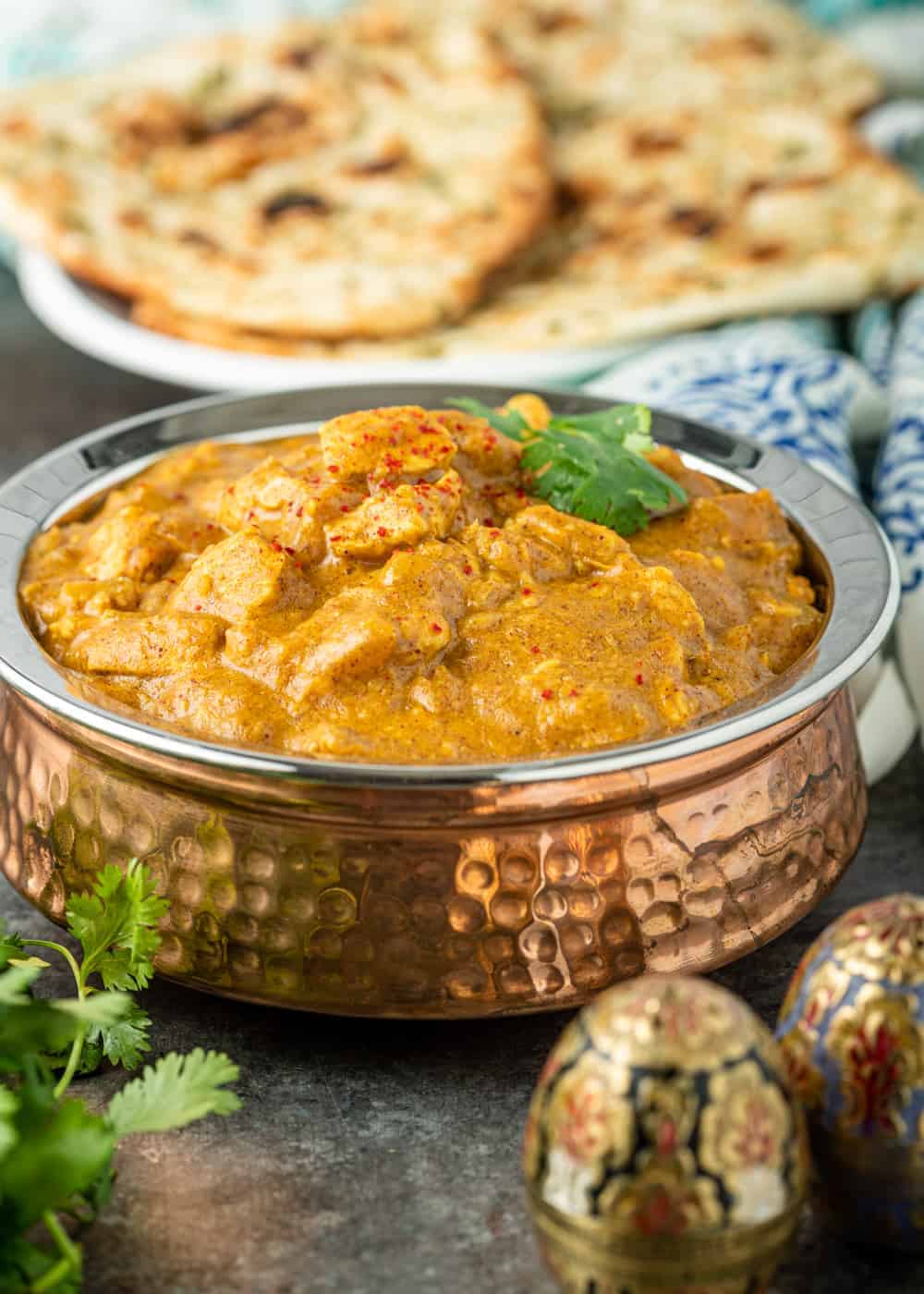 copper serving bowl filled with Indian chicken curry in a creamy sauce