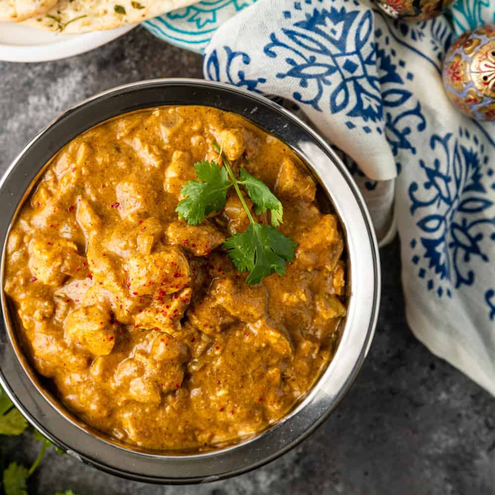 overhead image of chicken korma in silver colored serving bowl