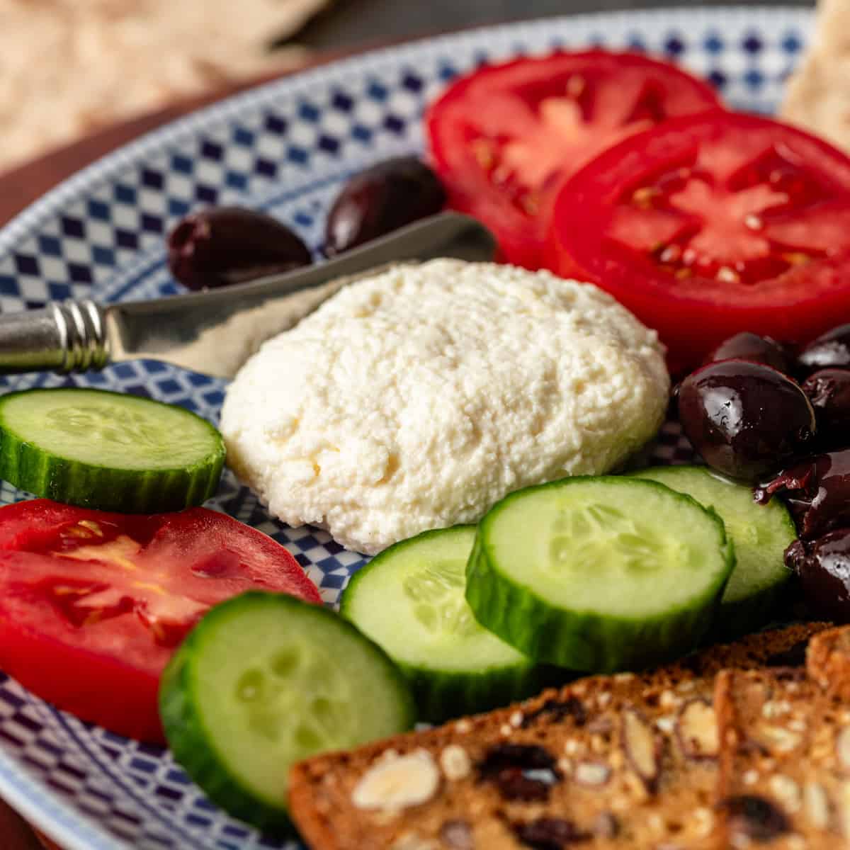 closeup: lebanese white cheese (jibin) on a plate with sliced tomatoes and cucumbers and black olives