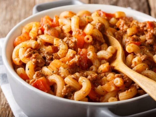 American Chop Suey (Hamburger Goulash with Elbow Macaroni), ground beef, tomatoes, tomato sauce and spices close-up in a white serving dish.