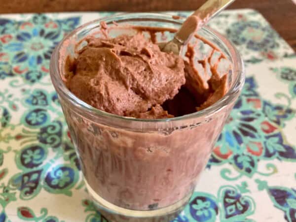 glass of greek yogurt pudding fluff with spoon it in on colorful placemat