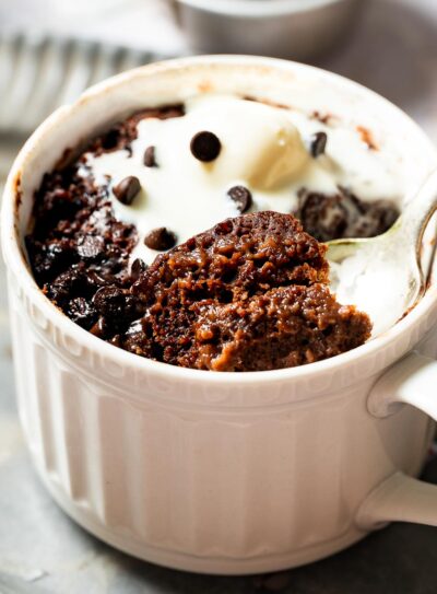 A vegan chocolate mug cake topped with dairy free ice cream.