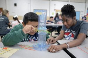 A youth mentor helps guide a Little through a stem activity.