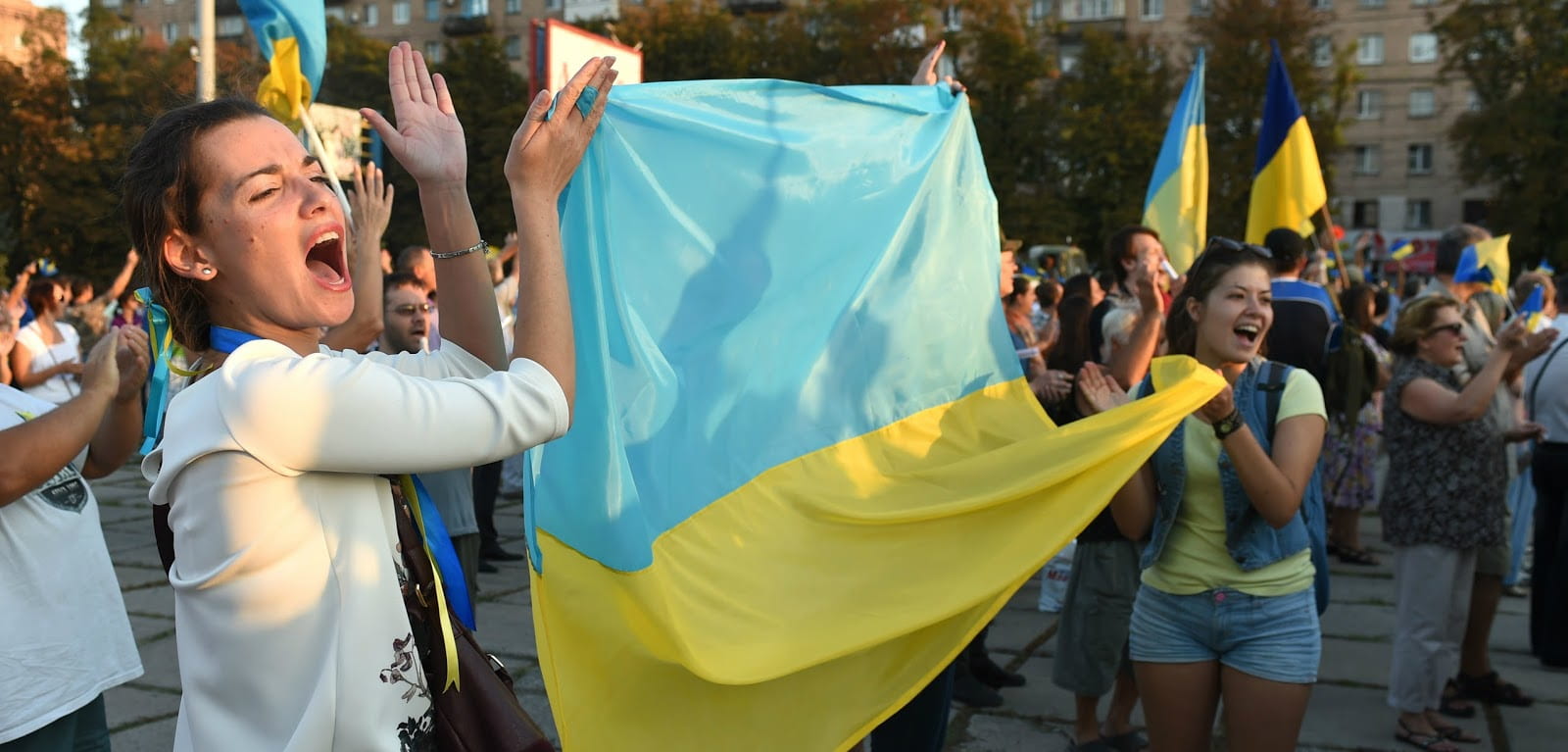 Two women holding the Ukrainian flag and shouting.