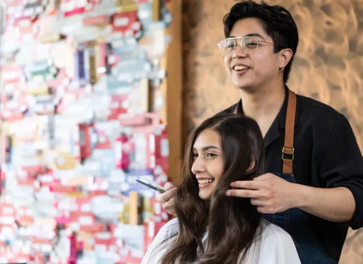 Young Asian hairdresser styles a young woman's hair at a salon