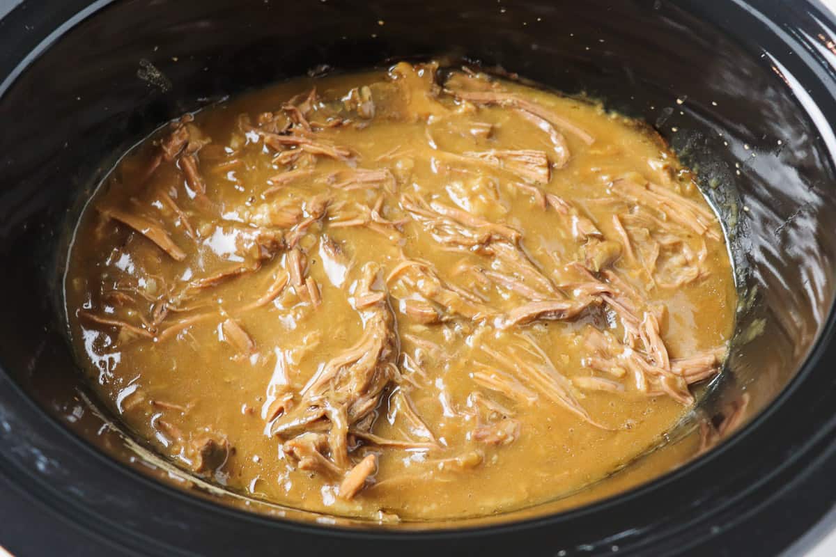 shredded pot roast with gravy inside crock pot