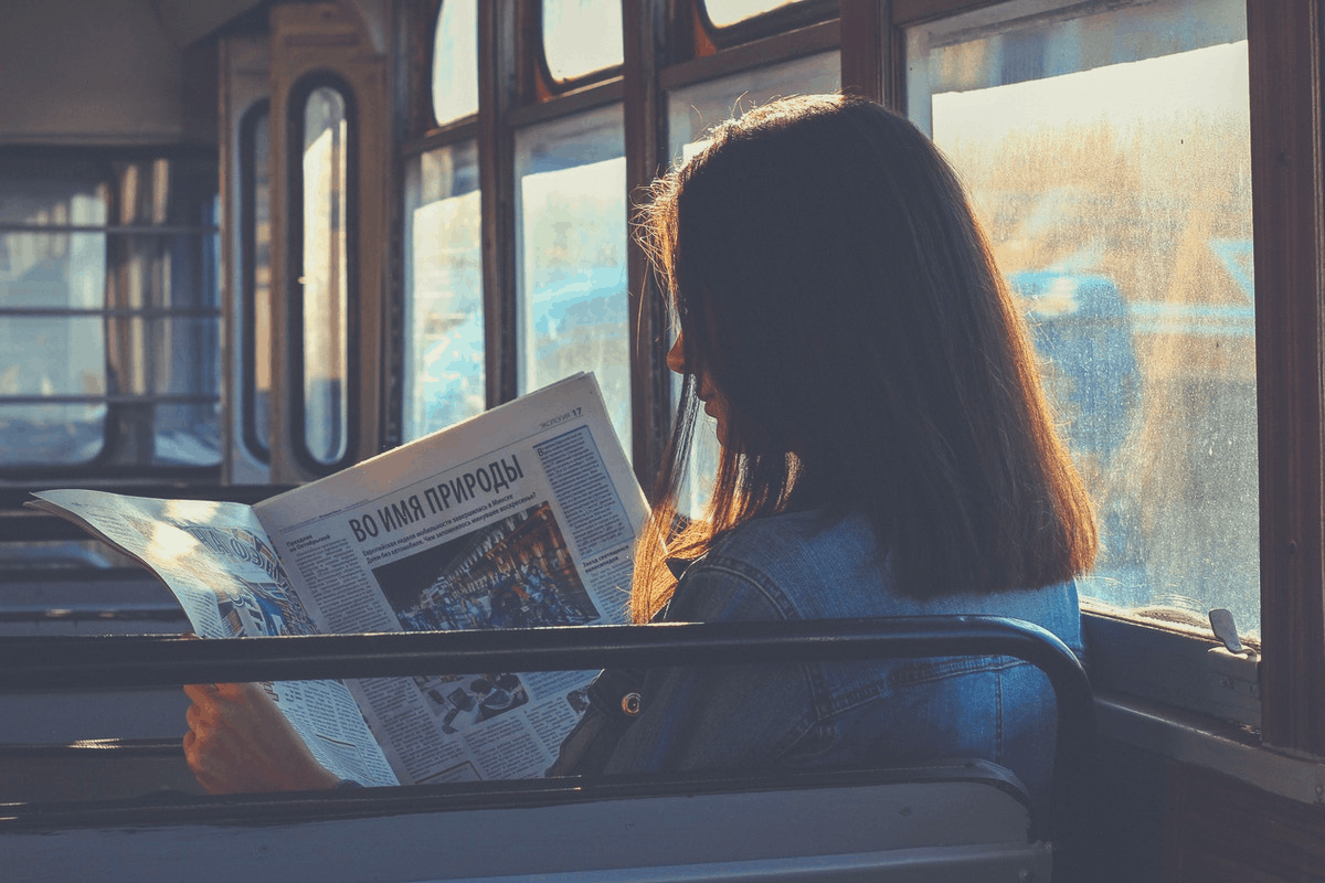 brunette reading a newspaper in the bus