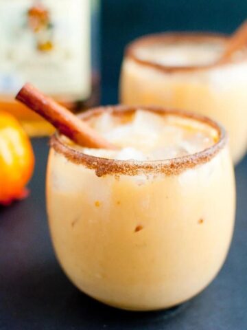 pumpkin horchata in a cinnamon sugar rimmed glass garnished with a cinnamon stick