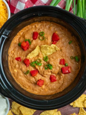 Overhead look at crock pot bean dip garnished with fresh veggies.