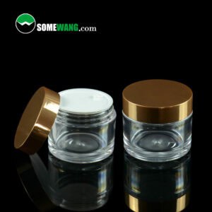 Deux pots de crème PETG transparent SWC-JBG50A de 50 g avec bouchons plaqués or sur fond sombre, affichant le logo « somewang.com » en haut.