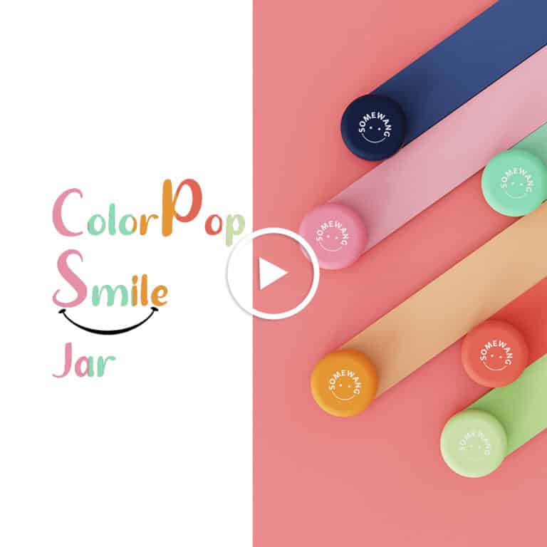 Реклама ColorPop Smile Jar: пять разноцветных баночек с крышками цвета макарон, расположенных по диагонали на розовой поверхности. Кнопка воспроизведения по центру.