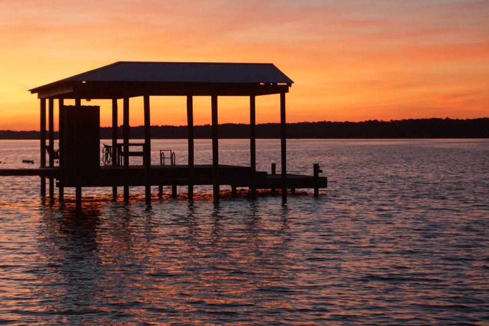 A small covered dock in a lagoon at sunset, one of the prettiest things to do in Gulf Shores AL. 