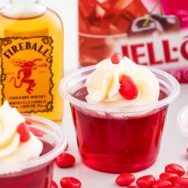 close up shot of fireball jello shots topped with whipped cream and cinnamon candies