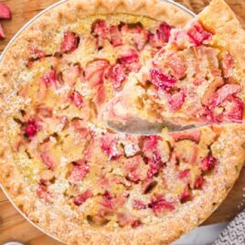 close up overhead shot of rhubarb custard pie with a slice being removed from the pie