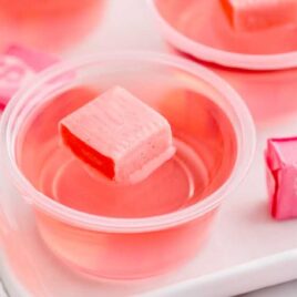 a close up shot of a Starburst Jello Shot in a cup topped with a pink starburst