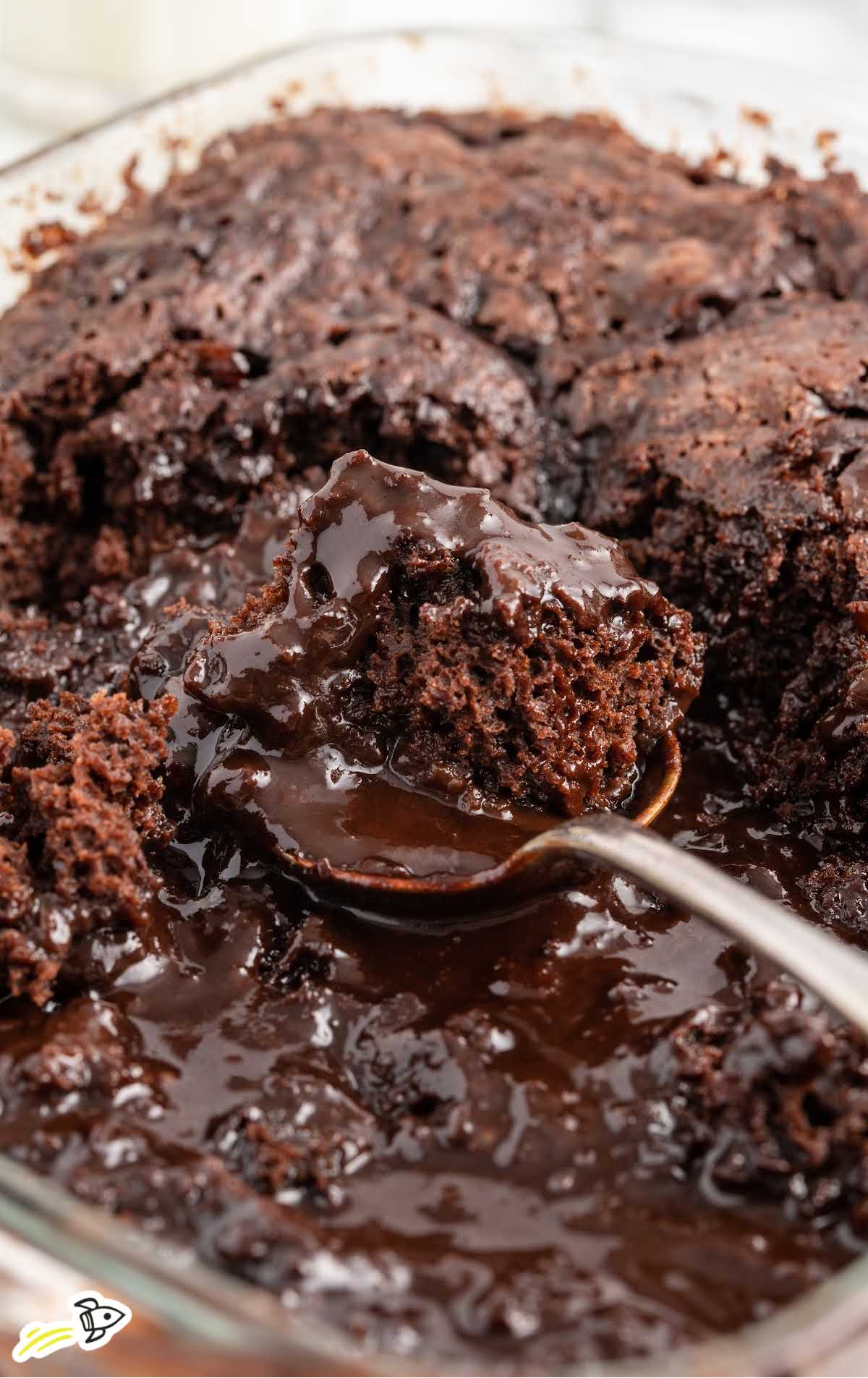 a close up shot of Pudding Cake with a spoon grabbing a piece in a baking dish