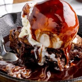 a close-up shot of a sliced of Sizzling Brownie in a pan with a spoon