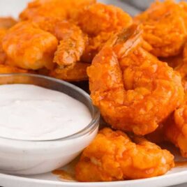 close up shot of a plate of Buffalo Shrimp served with a bowl of ranch