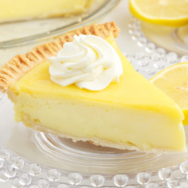 A slice of lemon custard pie with a dollop of whipped cream on top.