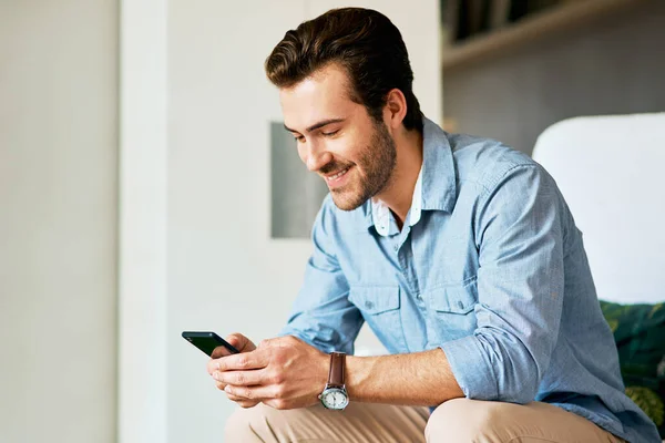 He cant miss out on what happens online. a handsome young man texting on a cellphone at home