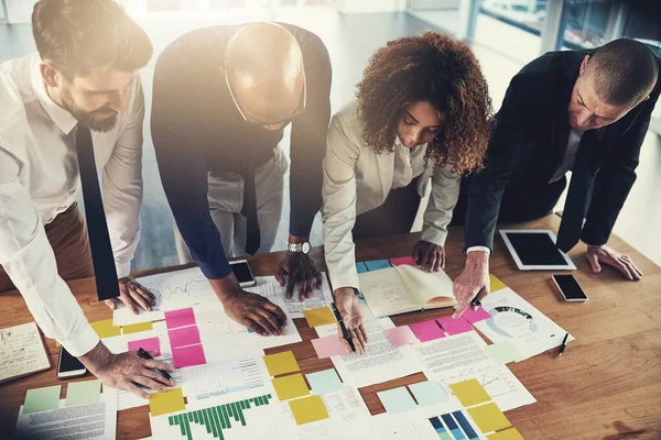 Together, they miss nothing. a group of businesspeople going over paperwork during a meeting in their office