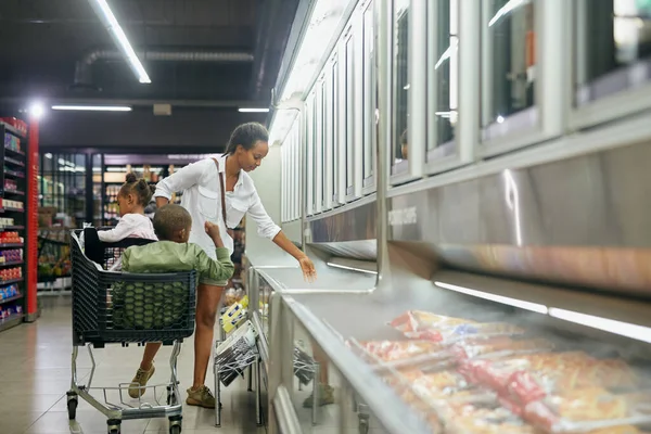 Through the produce aisle. Full length shot of a young mother doing grocery shopping with her kids