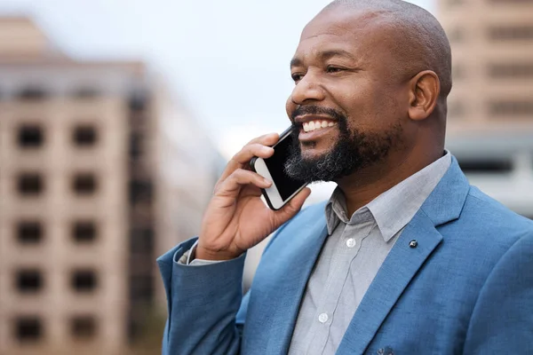 He never misses a chance to strike a new connection. a mature businessman talking on a cellphone while standing on a balcony outside an office