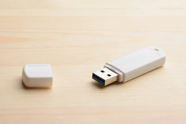 White USB stick with cap on a light wooden table