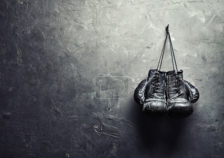 Foto de Guantes de boxeo viejos cuelgan de uñas en la pared de textura con espacio de copia para el texto. Concepto de jubilación - Imagen libre de derechos