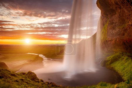 Foto de Seljalandsfoss es una de las cascadas más bellas de Islandia. Se encuentra en el sur de la isla. Esta foto se toma durante la increíble puesta de sol a aprox. 1 AM
. - Imagen libre de derechos