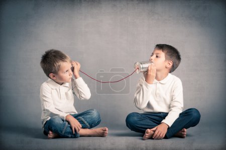 Foto de Los hermanos jóvenes que hablan con lata pueden telefonear sobre fondo grunge - Imagen libre de derechos