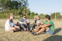 Friends sitting on grassy field — Stock Photo