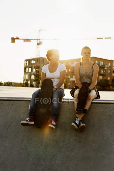 Friends sitting at edge of skateboard ramp — Stock Photo