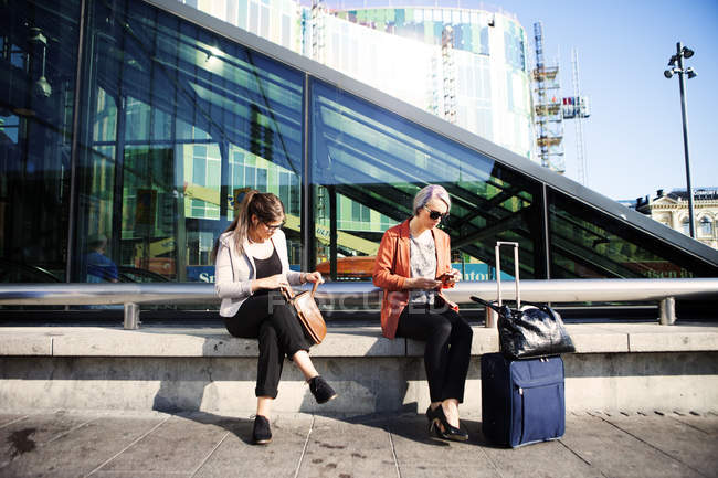 Businesswomen sitting on retaining wall — Stock Photo