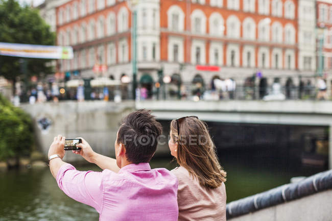 Man standing by friend photographing buildings — Stock Photo