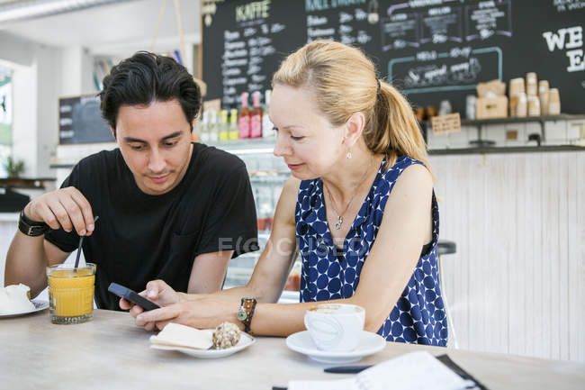 Friends using smartphone at table — Stock Photo