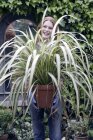 Cheerful woman holding potted plant. — Stock Photo