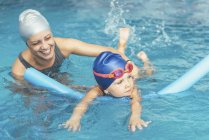 Little girl learning swimming with instructor in public pool. — Stock Photo