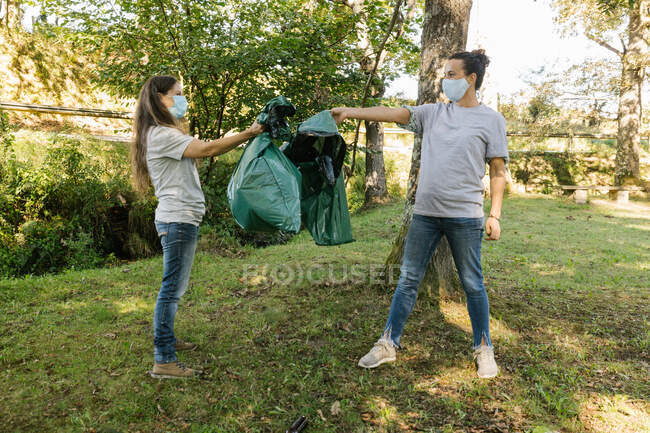 Coppia di volontari che tiene sacchi della spazzatura in una foresta. Concetto ecologico — Foto stock