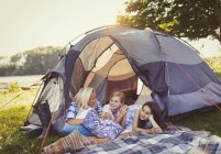 Mother and daughters talking and relaxing in tent at campsite — Stock Photo