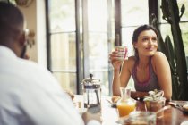 Smiling woman drinking coffee at breakfast table — Stock Photo