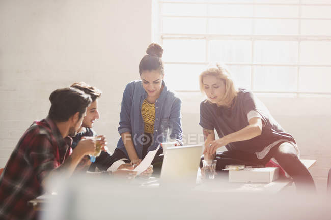 Creativi giovani uomini d'affari brainstorming al computer portatile in ufficio soleggiato — Foto stock